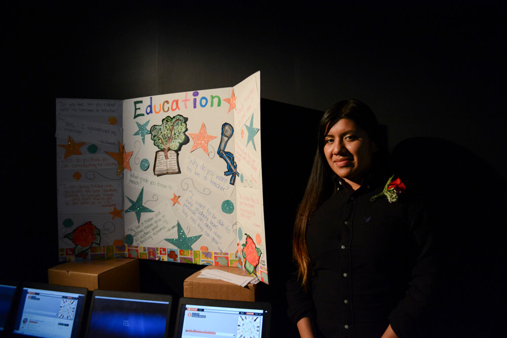 Photo of Lorena Alatorre standing next to her poster on education.