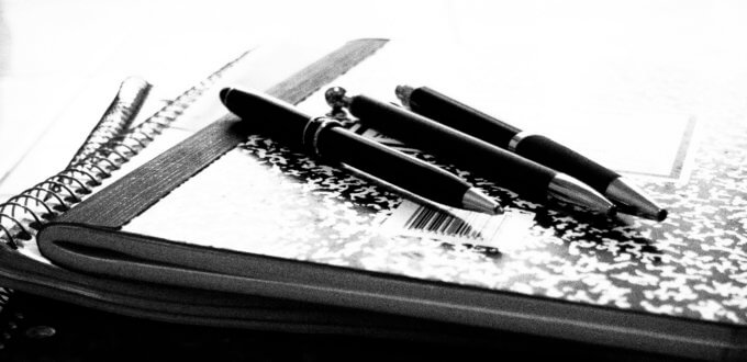 A photo of 3 pens on a composition book